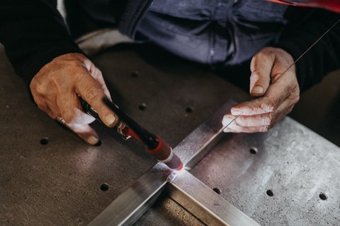 Mains d'un technicien travaillant une pièce métallique, reportage industriel