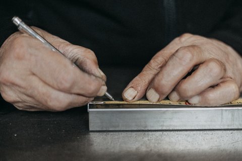 Main traçant un repère sur une pièce métallique, reportage en atelier